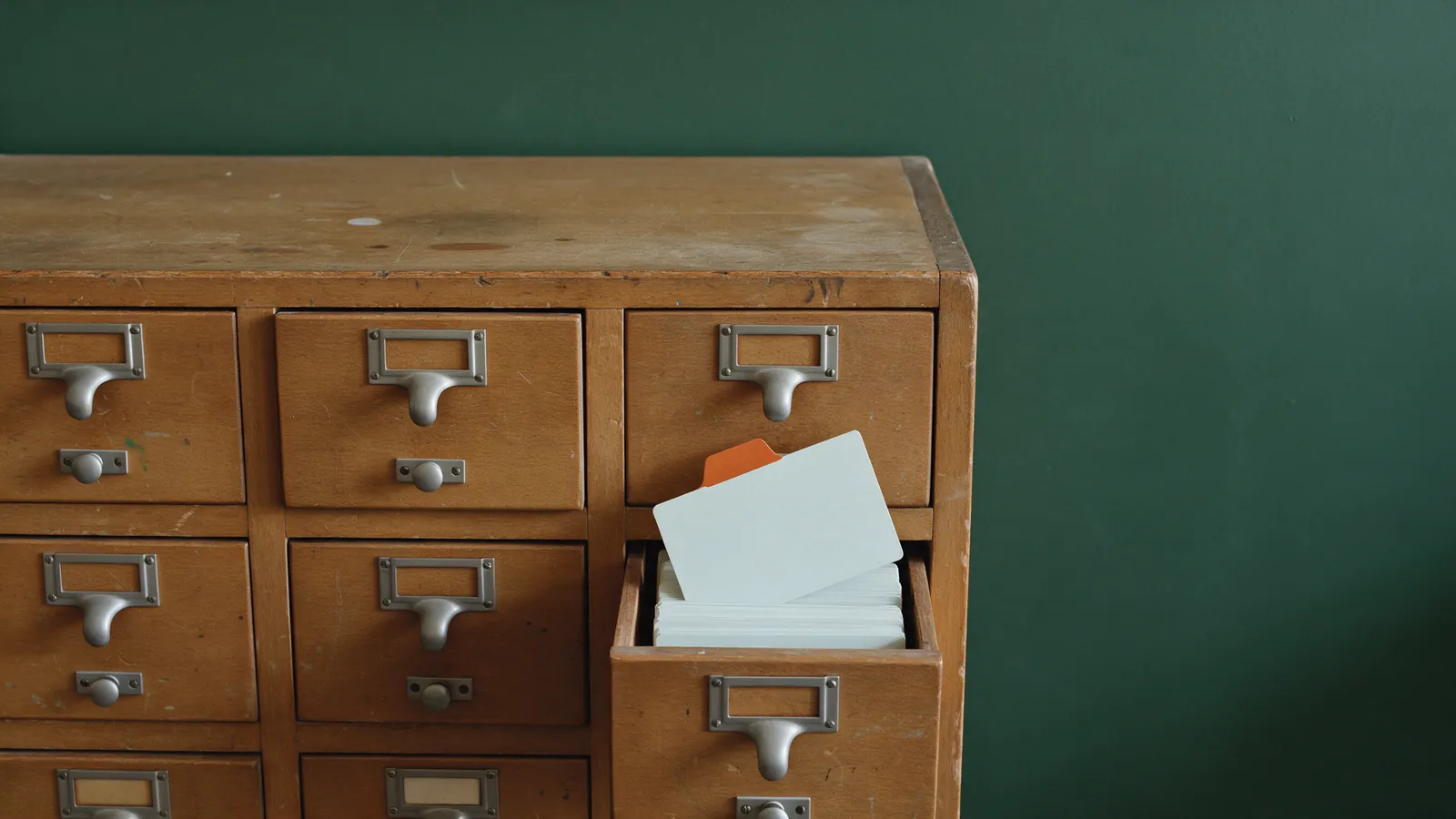 Fichero de biblioteca de madera con un cajón abierto y una ficha marcada en naranja